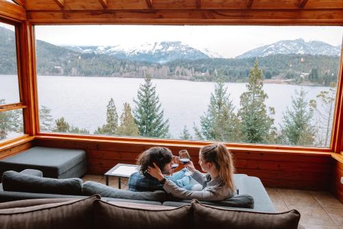 two people sitting in a room with a large window at Peninsula Petit in San Carlos de Bariloche
