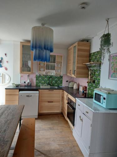 - une cuisine avec des placards en bois et un four micro-ondes bleu dans l'établissement Portobello Charming Seaside 3-BR Holiday Apartment, à Édimbourg