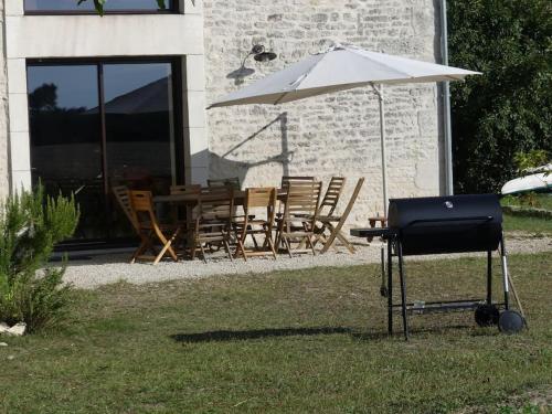 uma grelha com um guarda-sol, uma mesa e cadeiras em Les Chouettes Blanches em Benet