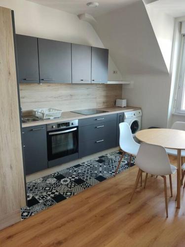 une cuisine avec des armoires bleues et une table et des chaises dans l'établissement Appartement centre-ville., à Crozon