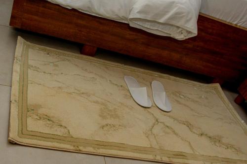 a pair of white slippers on a rug next to a bed at Velvet Suites in Kigali