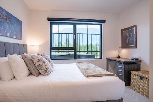 a bedroom with a large bed and a window at Revylation by Revelstoke Vacations in Revelstoke