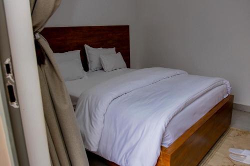a bedroom with a bed with white sheets and pillows at Velvet Suites in Kigali