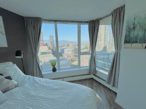 ein Schlafzimmer mit einem Bett und einem großen Fenster in der Unterkunft Downtown 4bd 2ba View Skytrain 2 Free Parking in Vancouver