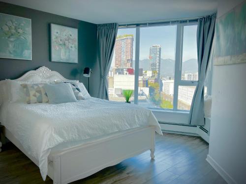 ein Schlafzimmer mit einem weißen Bett und einem großen Fenster in der Unterkunft Downtown 4bd 2ba View Skytrain 2 Free Parking in Vancouver