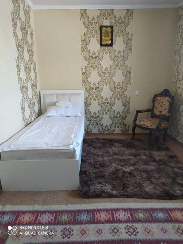 a bedroom with a white bed and a chair at Гостевой дом Энесай in Bishkek