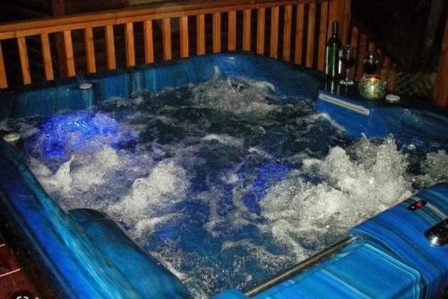 uma banheira azul cheia de água com uma garrafa de vinho em בקתות עץ סקנדינביות במטולה em Metula