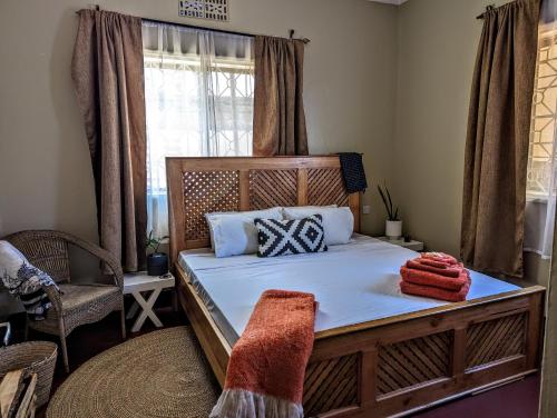 um quarto com uma cama, uma cadeira e uma janela em The Lion King Homestay em Moshi