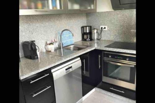 une cuisine avec un évier et une cuisinière dans l'établissement Proche PARIS/Casino d’Enghien/stade de France/CDG, à Eaubonne