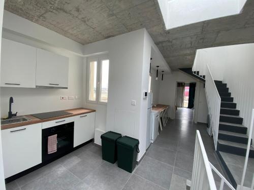 a kitchen with white cabinets and a staircase at Minimal & Arty Townhouse in Hamrun