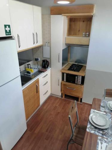 a small kitchen with white cabinets and a wooden table at Angel's Houses in Skala Kallonis