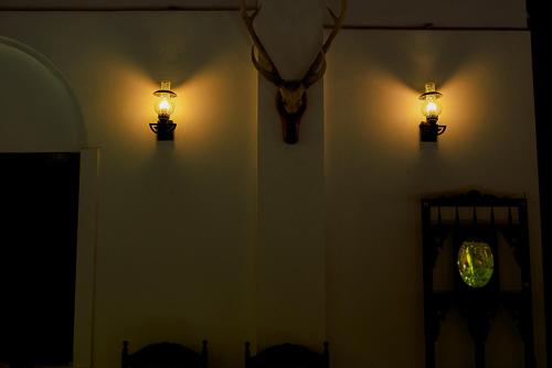 two lights on a wall with a deer head and a clock at Walawwa Matale in Matale