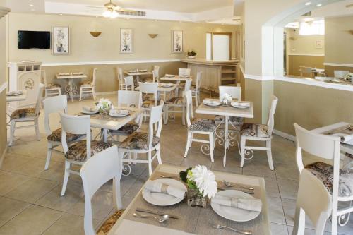 a restaurant with white tables and chairs and a counter at Hotel & Suites Quinta Magna in Guadalajara