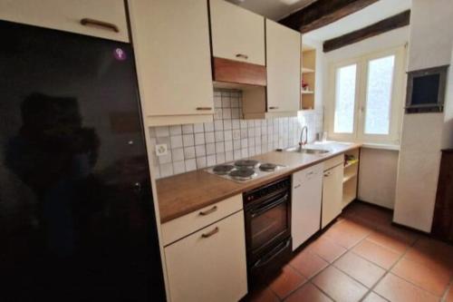 eine Küche mit weißen Schränken und einem schwarzen Kühlschrank in der Unterkunft Casa Alta in Lugano