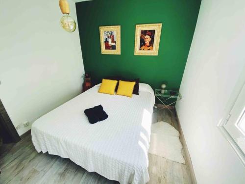 ein Schlafzimmer mit einem weißen Bett mit gelben Kissen und einer grünen Wand in der Unterkunft Precioso apartamento con bañera hidromasaje in Sopelana