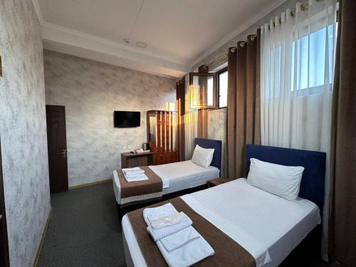 a hotel room with two beds and a television at Al Arda Avenue in Tashkent