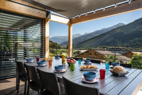 d'une table sur un balcon avec vue sur les montagnes. dans l'établissement Chalet neuf, Jacuzzi, piscine privée mai-sept, pétanque, proche Paradiski, à Aime La Plagne