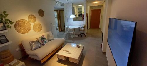 uma sala de estar com um sofá e uma televisão em Apartamento en el Zapillo, Las Conchas II em Almeria