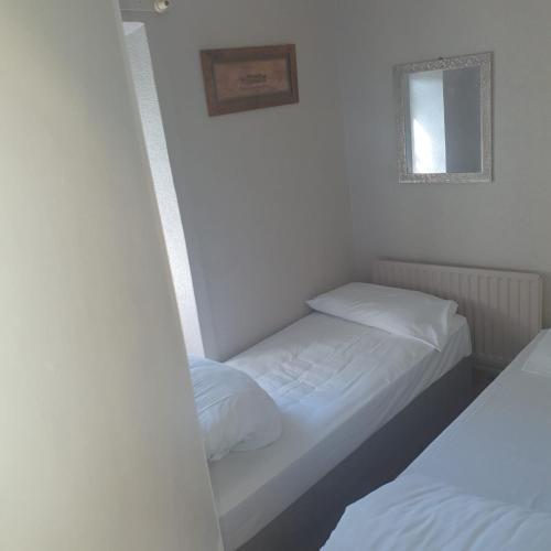 2 łóżka w małym pokoju z białymi ścianami w obiekcie 1 James Green w mieście Kilkenny