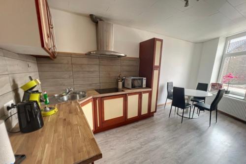 a kitchen with a sink and a table with chairs at Charbonnel 1 B Charleroi-airport in Charleroi