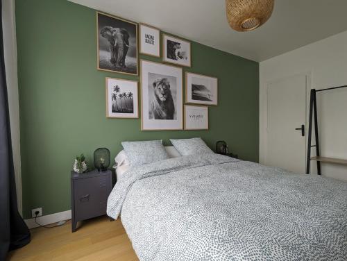 een slaapkamer met een groot bed en foto's aan de muur bij Appt cosy en cœur de ville proche Lille - 15 min in Tourcoing