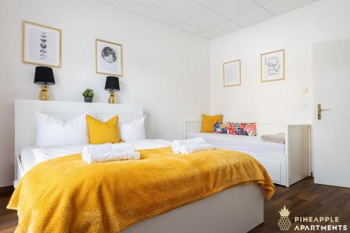 a bedroom with a large bed with a yellow blanket at Pineapple Apartments Dresden Mitte - free parking in Dresden