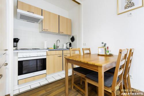 cocina con mesa de madera, fogones y horno en Pineapple Apartments Dresden Mitte - free parking, en Dresden
