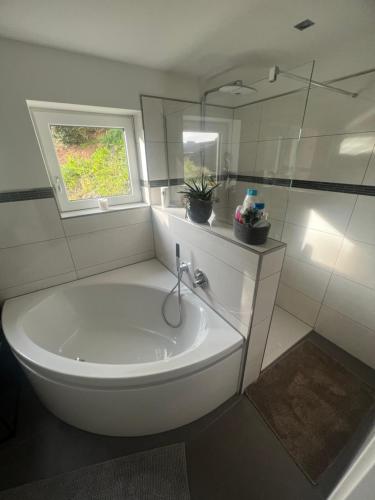 een witte badkamer met een bad en een raam bij Puppenhaus 