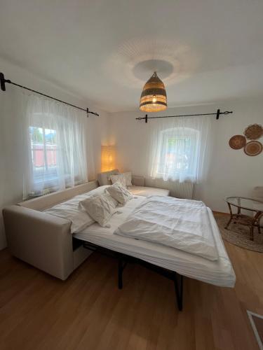 a large white bed in a room with windows at Boho Home am Bach in Altmünster
