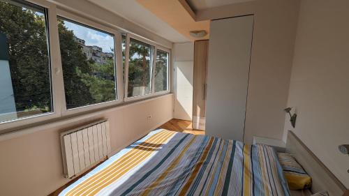 ein Schlafzimmer mit einem Bett und zwei Fenstern in der Unterkunft Modern and cozy apartment, excellent location, near Sarajevo City Center, 60m2 in Sarajevo