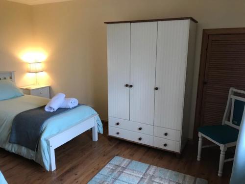 a bedroom with a bed and a cabinet and a chair at Harsgeir View Holiday Cottage -Wifi Go green in Breaclete