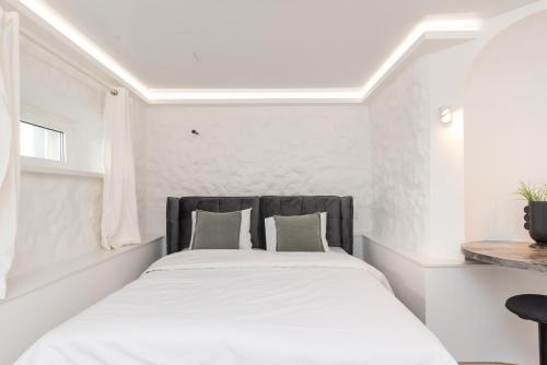 a white bedroom with a large bed with a black headboard at Hilltop Apartments - City Centre in Tallinn
