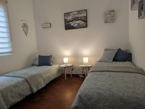 two beds in a room with two lamps on tables at Casa Ascenção, vista mar Madeira in Funchal