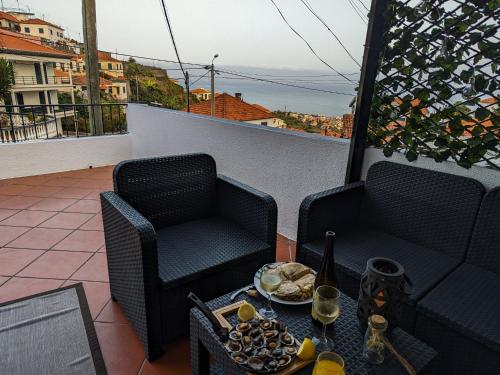 un balcón con 2 sillas y una mesa con comida en Casa Ascenção, vista mar Madeira en Funchal