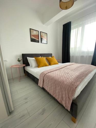 una camera da letto con un letto con cuscini gialli e una finestra di Orhideea Central Apartments a Bucarest
