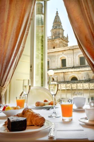 a table with a plate of food and wine glasses at Relais Antica Badia - San Maurizio 1619 in Ragusa