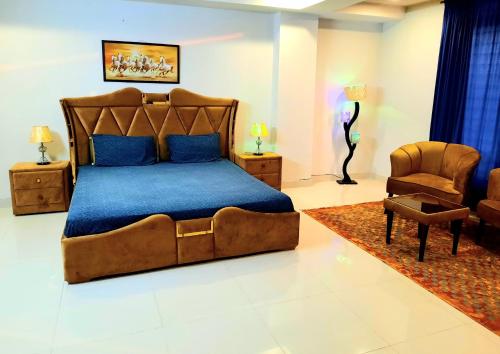 a bedroom with a large bed and a chair at Anabi Apartments and Suits E11 Islamabad in Islamabad