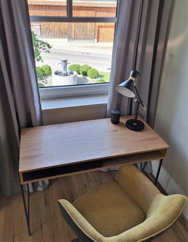 a desk with a lamp and a chair in front of a window at Design Apartment an der Via Claudia in Oberigling