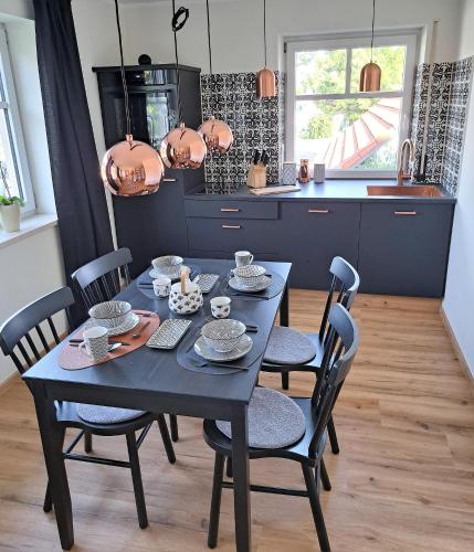 a dining room table with chairs and a blue kitchen at Design Apartment an der Via Claudia in Oberigling