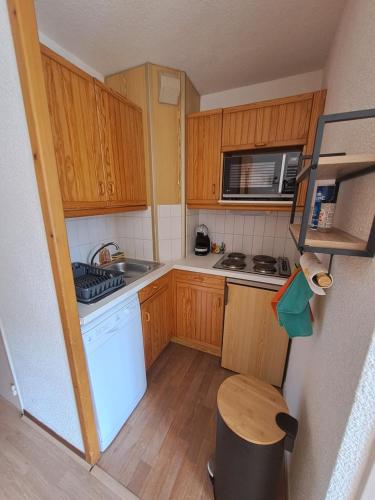 uma pequena cozinha com armários de madeira e electrodomésticos brancos em Le Lou&My à Valmeinier 1800 em Valmeinier