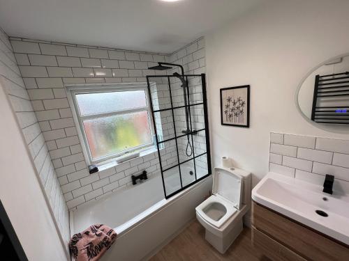 baño con aseo y lavabo y ventana en Altrincham Terrace - 2 Bedroom House - Free Parking - Sleeps 6 - Near Tram Stop, en Mánchester