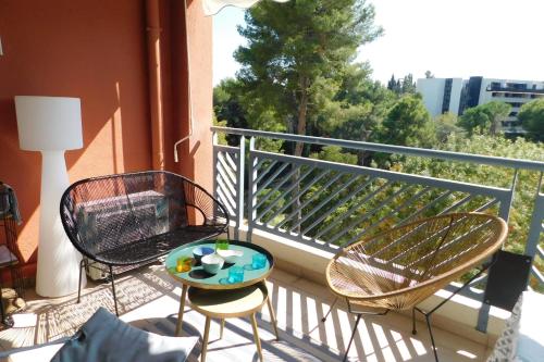a balcony with two chairs and a table on it at Standing T2 Domaine des palmiers air-conditioned with parking and pool in Cannes