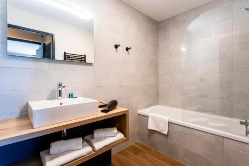 a bathroom with a sink and a bath tub at Résidence Club MMV Le Silvana in Risoul