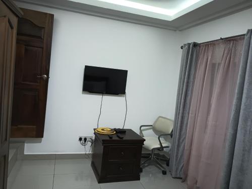 a room with a chair and a television on a wall at Himma's Apartments in Adonkia
