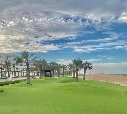 un campo da golf con palme e un edificio di الشاليه الملكى غرفتين وصاله vip منتجع بورتو سعيد a `Ezbet Shalabi el-Rûdi