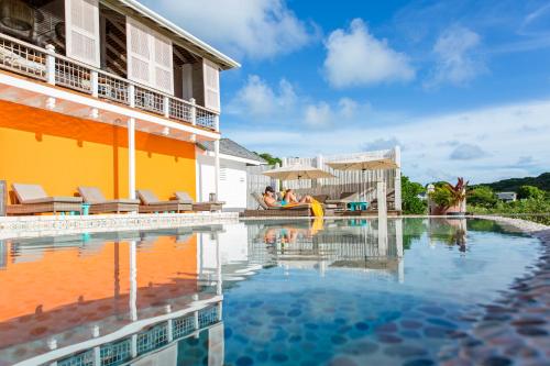 a pool in front of a house with two people sitting on a raft at Escape at Nonsuch Bay Antigua - All Inclusive - Adults Only in Gaynors