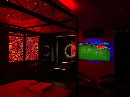 a room with a tv and a soccer game on the screen at Chambre Romantique avec Jacuzzi R in Gruny