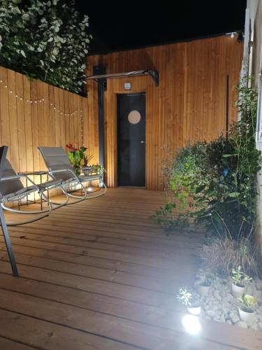 a wooden deck with two chairs and a door at Serenity Indepedent Suite near to Disneyland & Paris in Bussy-Saint-Georges