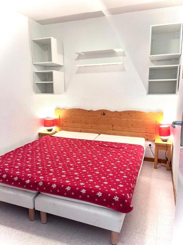 une chambre avec un grand lit avec une couverture rouge dans l'établissement APPARTEMENT CHALETS DU SUPER D, à Saint-Étienne-en-Dévoluy