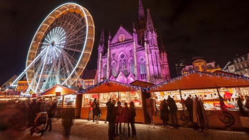 a christmas market in front of a cathedral with a ferris wheel at Petite maison au calme avec jardin clôturé les animaux bienvenue in Mollau